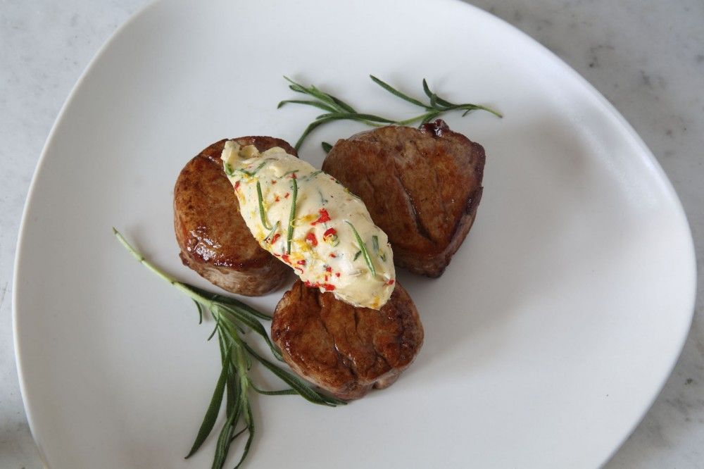 Grillat kött med kryddsmör på ligger på tallrik.