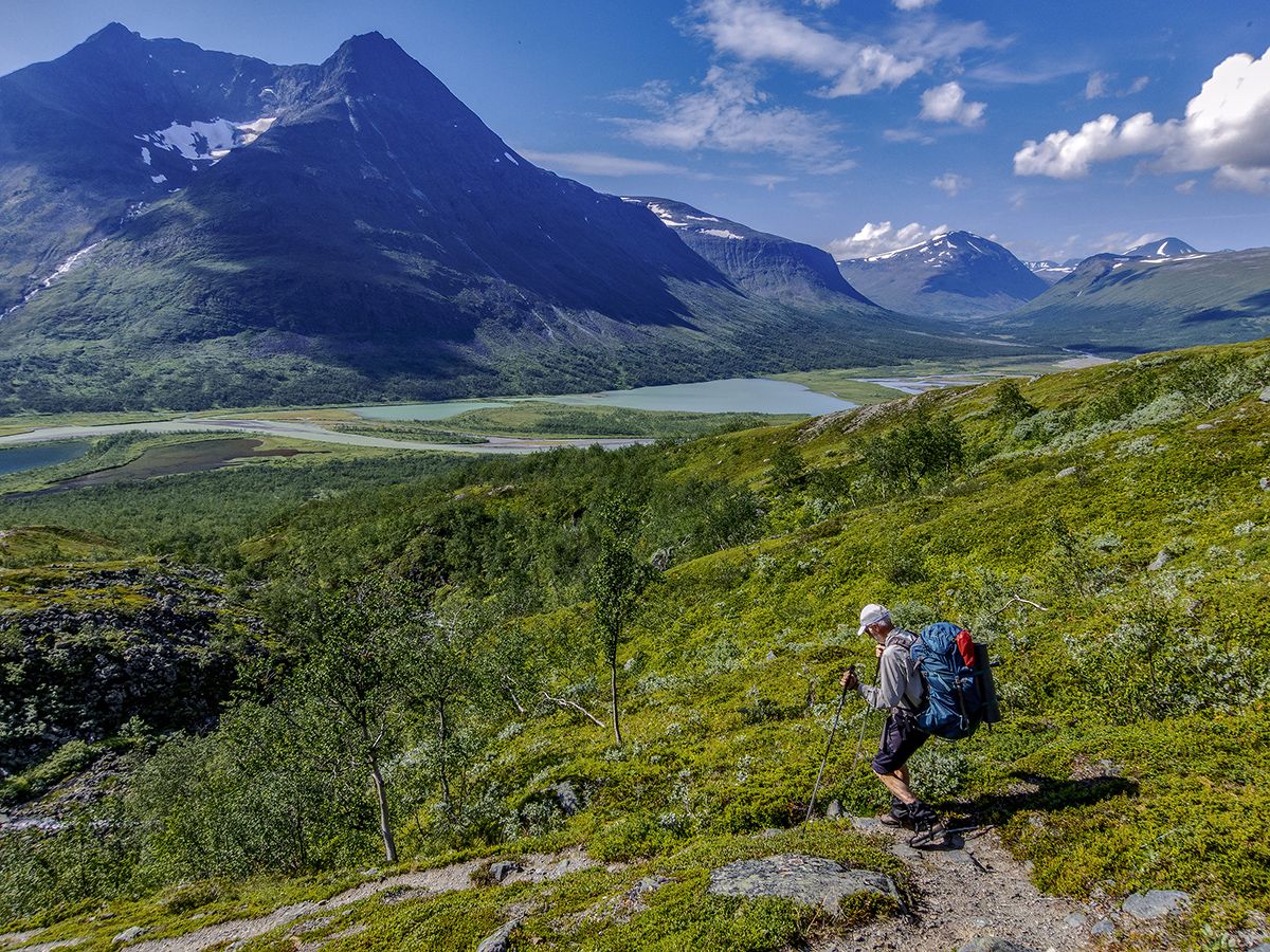 Vandrare med ryggsäck vid Rapaselet, med sjö och höga berg i bakgrunden