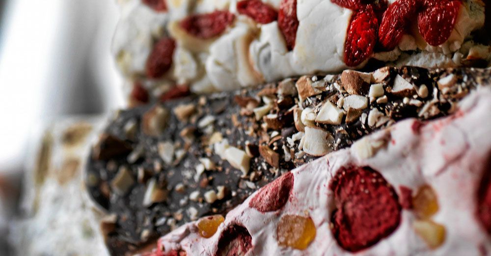 Närbild på olika sorters nougat med nötter och bär.