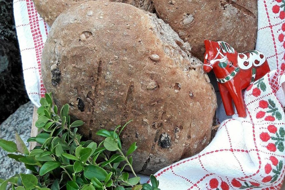 Nybakat bröd med en trädalhäst och örter på en duk.