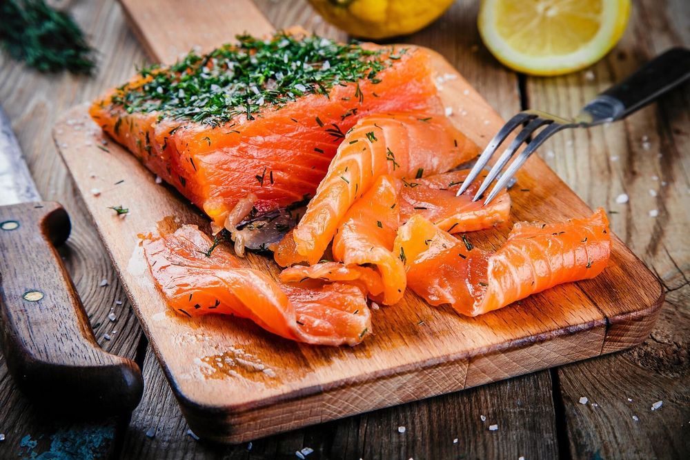 Gravad lax på skärbräda med dill och citron.