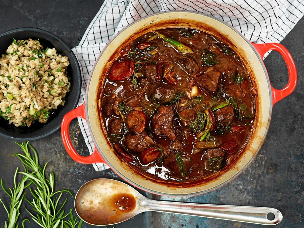 Gryta med kött och grönsaker i röd kastrull, serverad med risblandning.