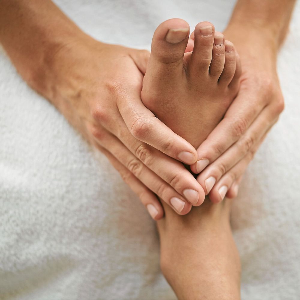Fot i närbild som får massage av ett par händer.