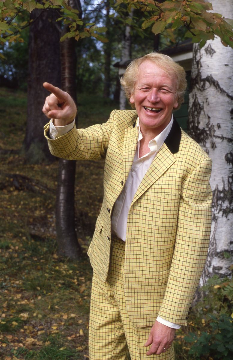 Thore Skogman i gulrutig kostym pekar och ler.