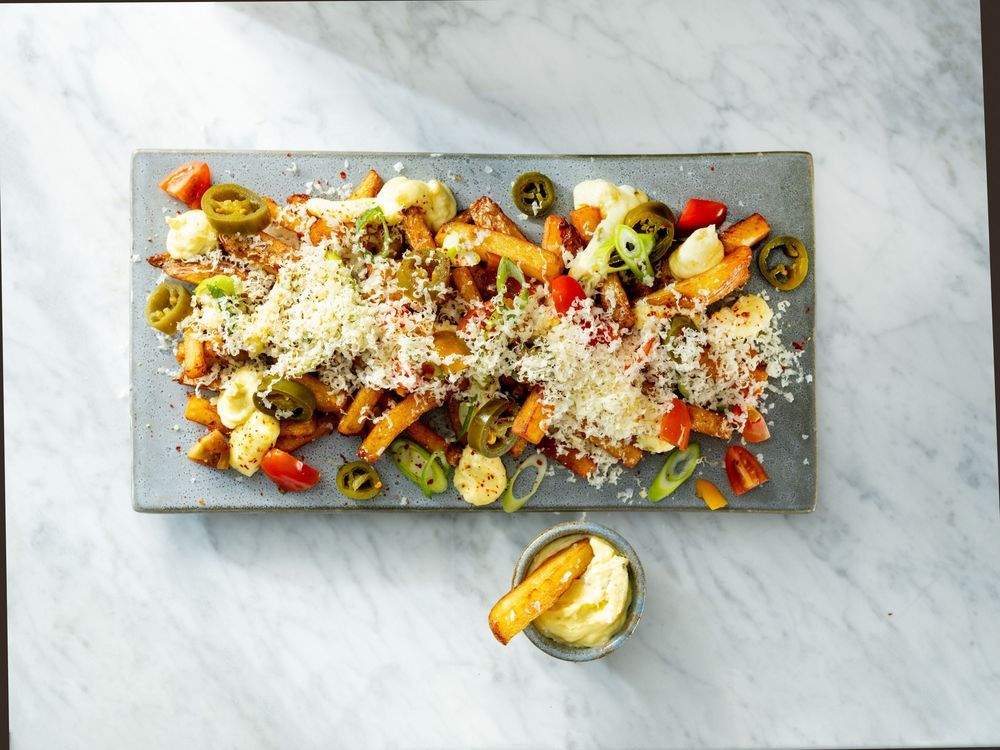 Läcker rätt med pommes, jalapeños och ost på fat.