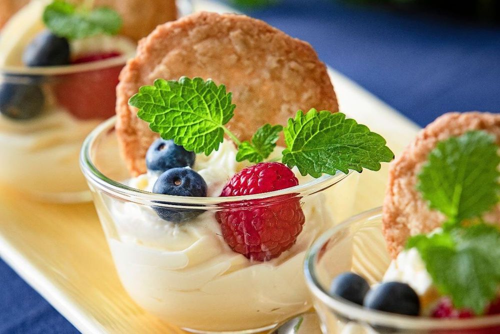 Dessertglas med grädde, färska bär, citronmeliss och knaprig kaka på toppen