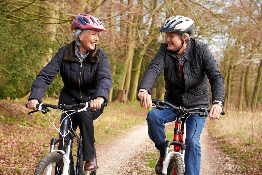 Man och kvinna cyklar på grusväg på varsin cykel.