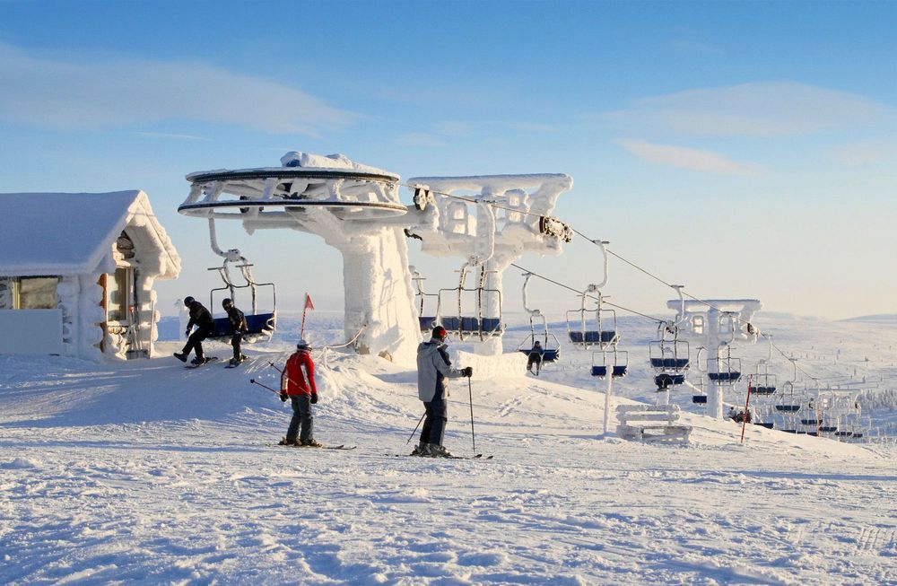 Snötäckt skidlift och skidåkare i soligt väder.