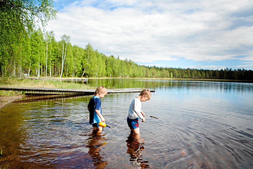 4-årige Sid och 5-årige Bo doppar fötter och ben i det än så länge ganska kyliga vattnet i sjön Grejsen.