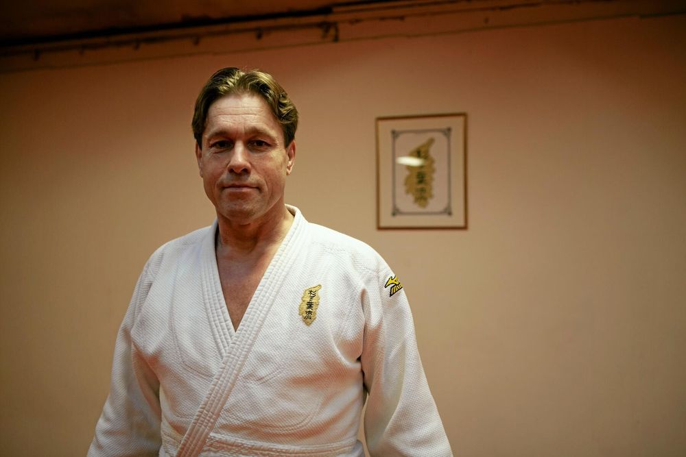 Magnus Cederblad i vit judodräkt står i ett träningsrum med ljus vägg och tavla bakom