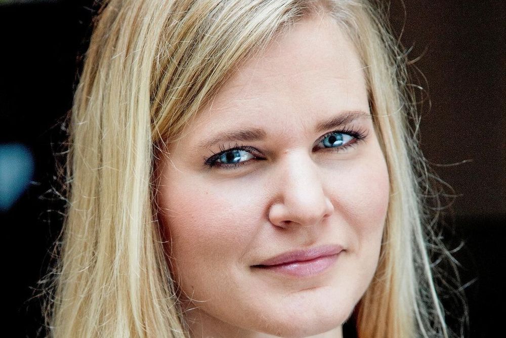 Porträtt av leende kvinna med långt blont hår och blå ögon, närbild utomhus