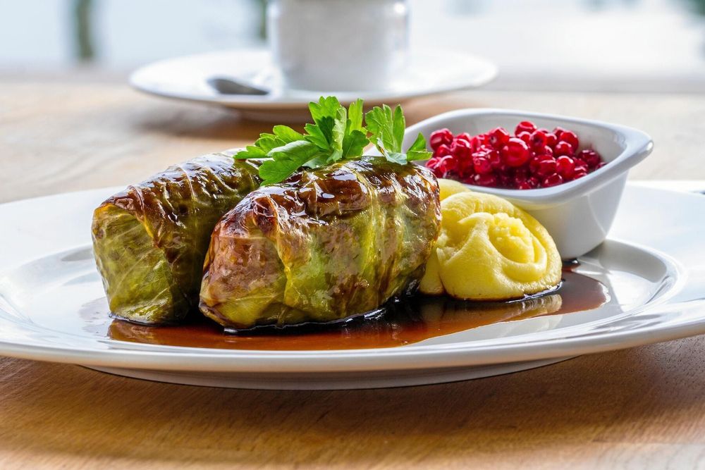 Tallrik med kåldolmar, potatismos, brunsås och lingon serverade på bord