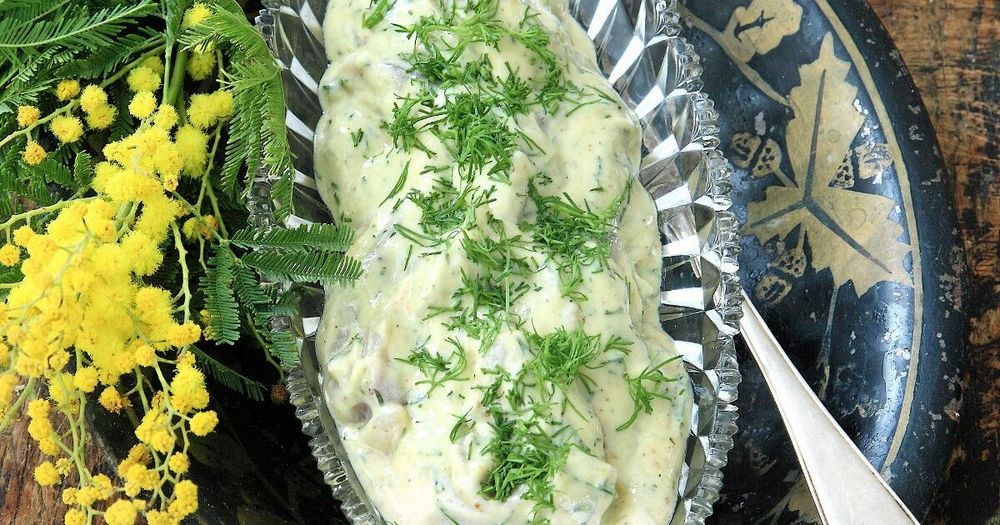 Krämig sill med dill i serveringsskål med blommor bredvid.