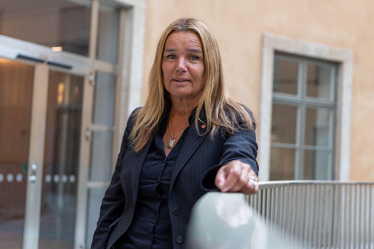 Kvinna i mörk kavaj står vid ett räcke i en ljus inomhusmiljö