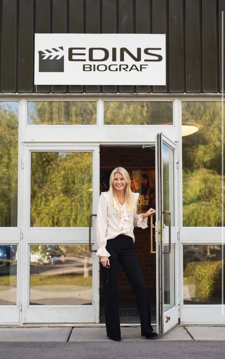 Tilde Edin står i entrén till Edins Biograf och håller upp dörren