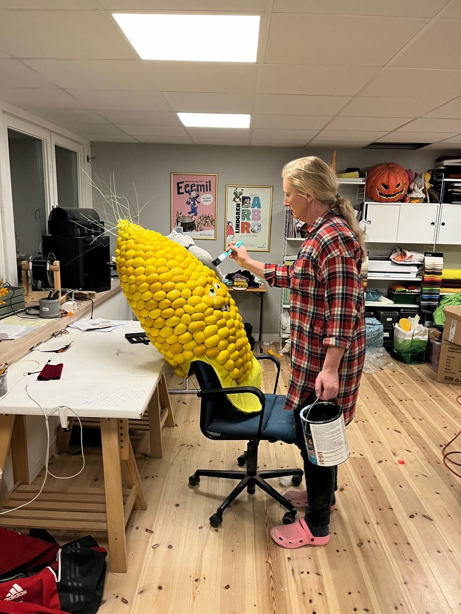 Eva-Karin målar en stor majskolvskostym av gula bollar i ett pysselrum