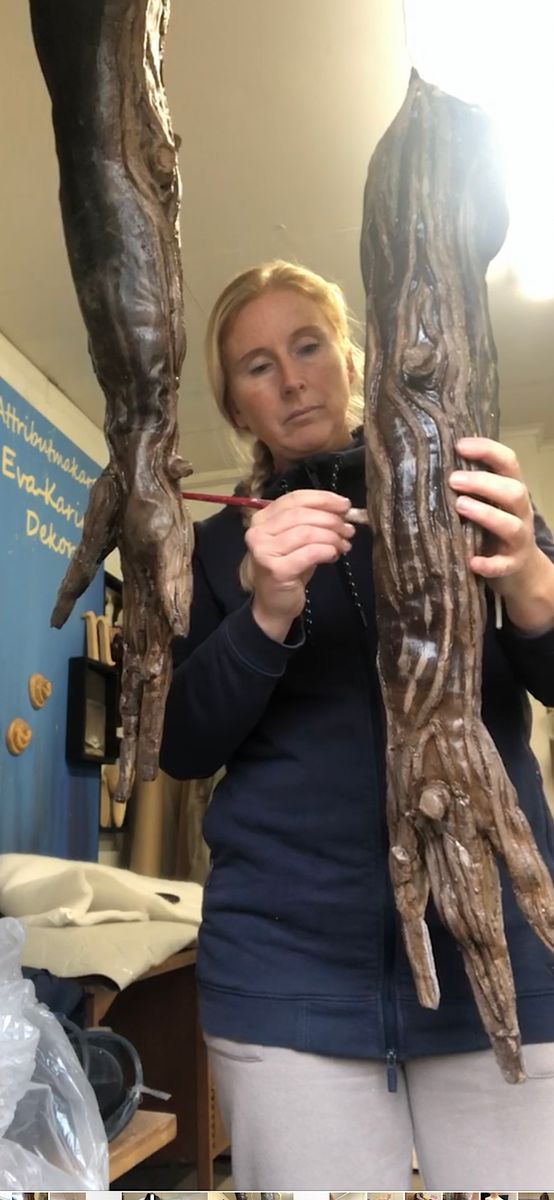 Eva-Karin målar på bruna armar av trä i en ateljé.