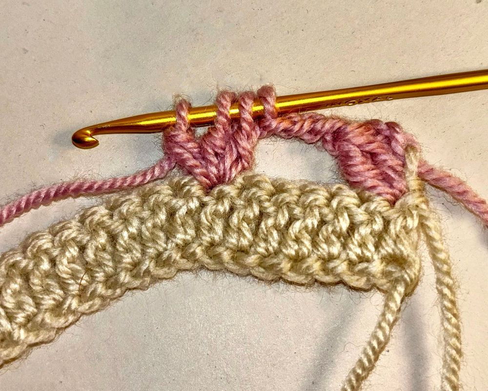 Virkning med rosa och beige garn på virknål.