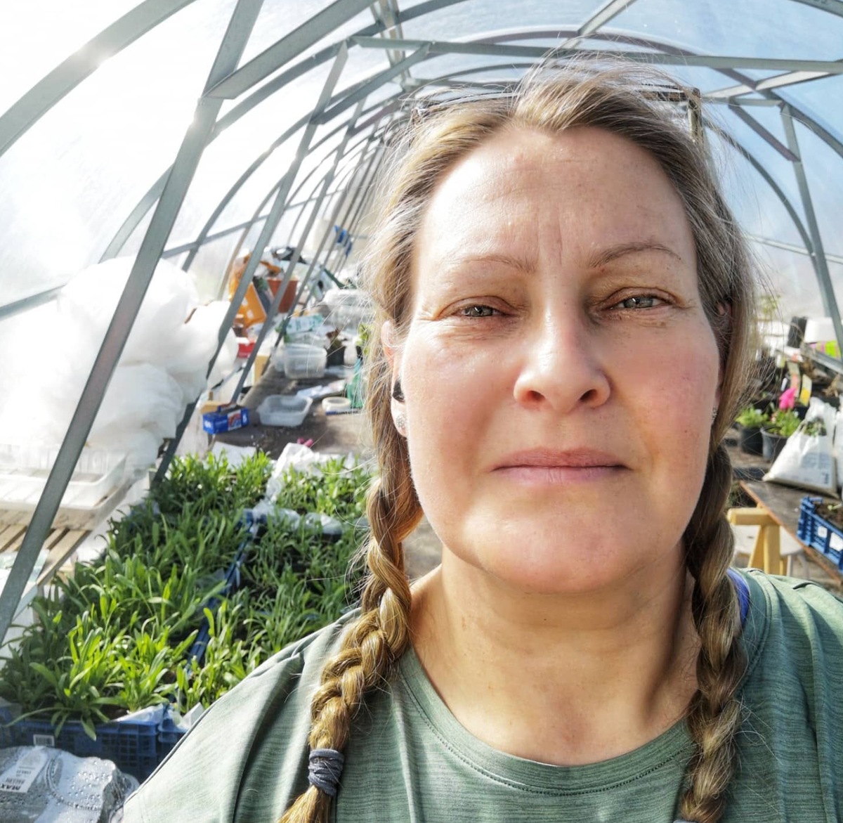 Porträttbild av Caroline Jonsson i växthus omgivet av gröna plantor