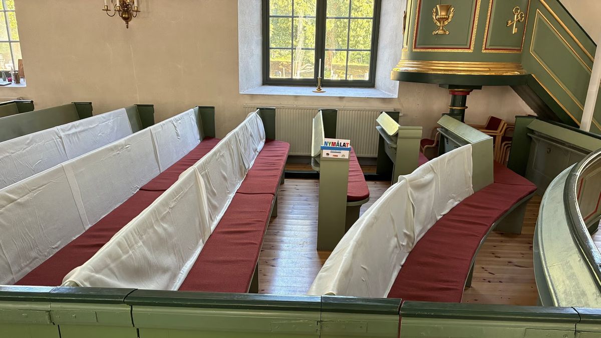 Tomma kyrkbänkar med röda dynor i en Bergs kyrka, en äldre landsbygdskyrka
