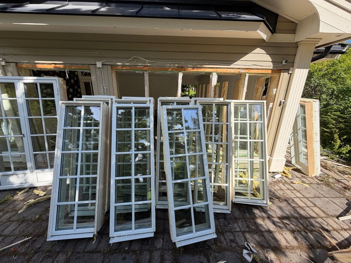 Borttagna spröjsade fönster står lutade mot ett hus under renovering