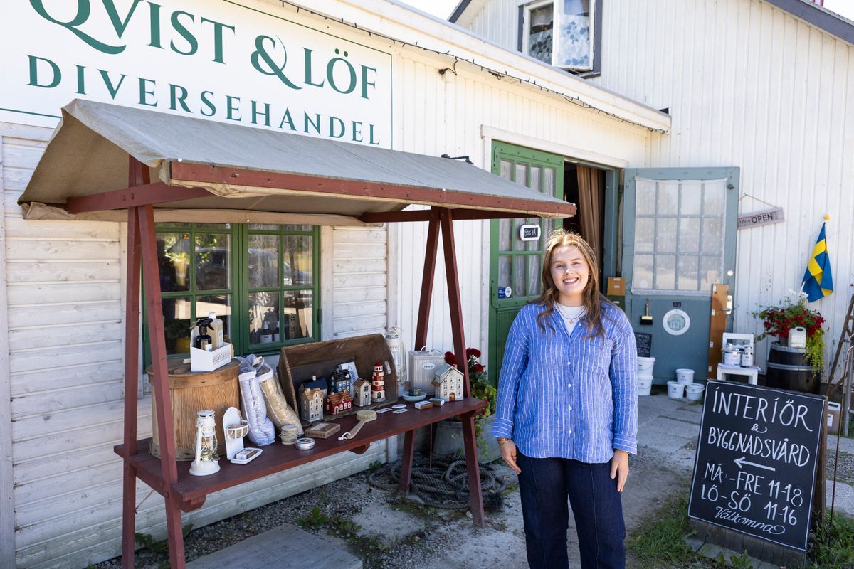 Leende Josefina Sjöqvist framför lantlig diversehandel med inredning utställd utanför