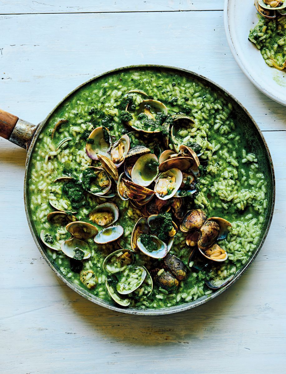 Grön risotto med musslor och svamp i stekpanna på ljust bord
