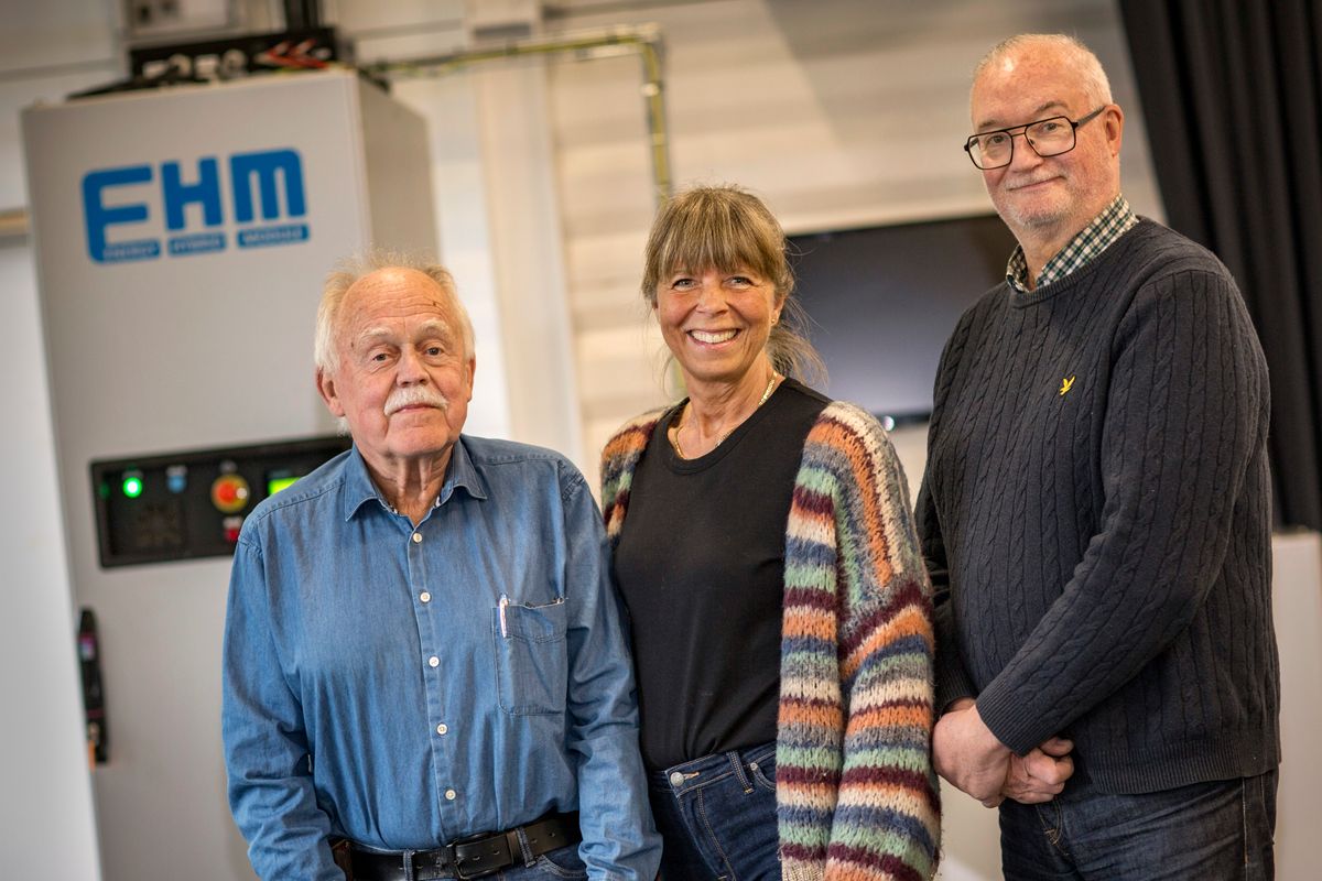 Tre personer står framför en maskin märkt FHM i en industrilokal