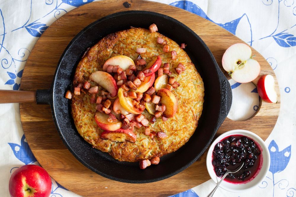 Rösti i stekpanna toppad med bacon och äpplen.