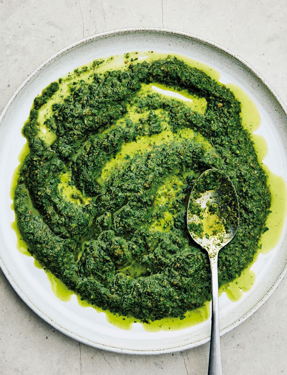 Tallrik med grön örtig sås, salsa verde, med en sked i såsen