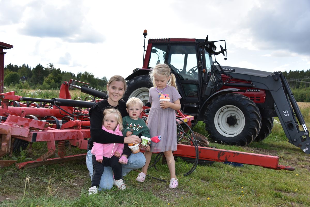 Leende Sofie Heinered I Grums med tre barn framför röd traktor på lantgård