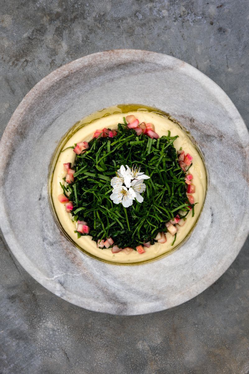 Skål med sotad svartkål och bönkräm med dekorativ blomma på toppen