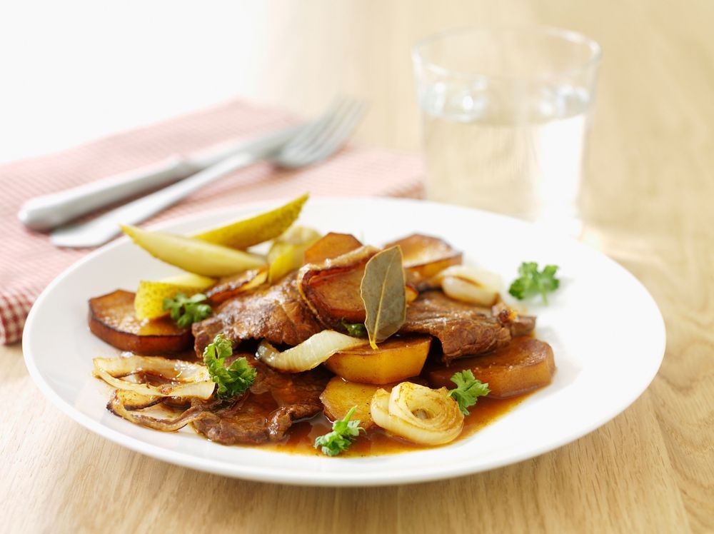 Sjömansbiff med potatis, lök och päron på en tallrik.