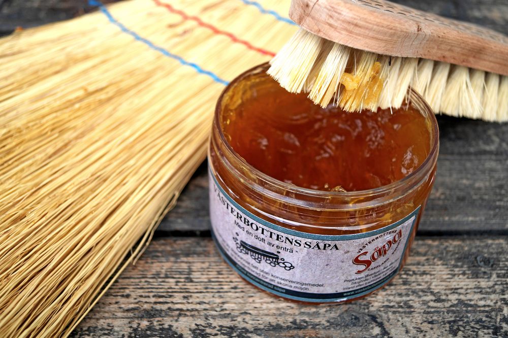 Burk med såpa och skurborste på trädäck.