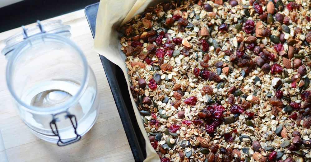 Hemmagjord müsli på plåt med nötter, frön och bär, redo att hällas i burk