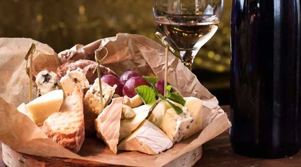 Ostbricka med vindruvor och ett glas vin.