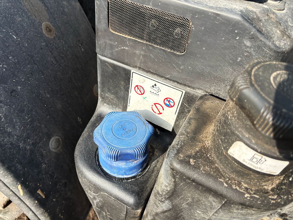 Blå plastkork och varningsdekaler på smutsig maskindel utomhus