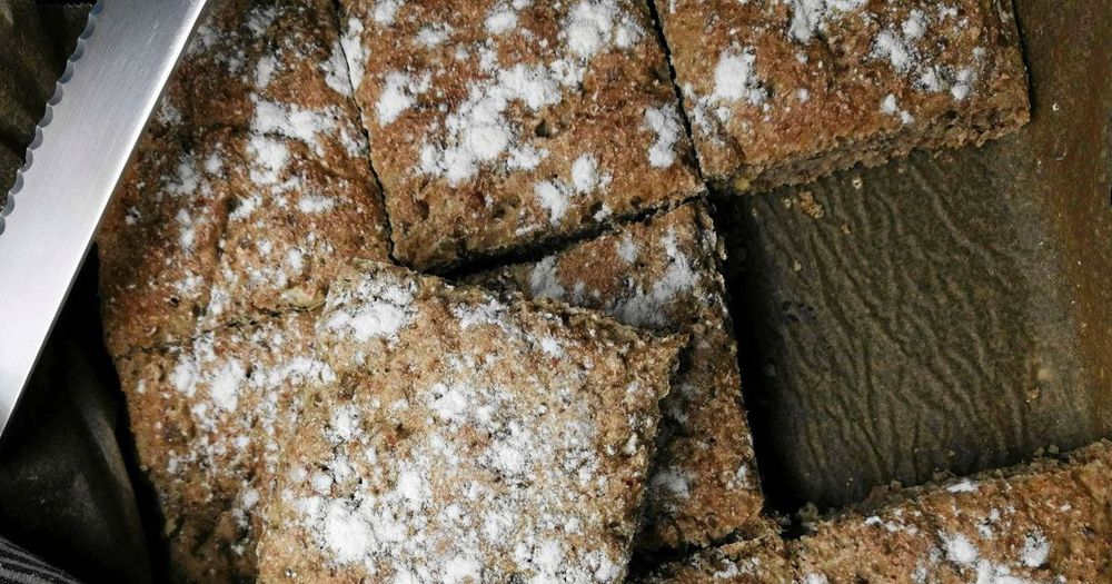 Grovbakade brödrutor med mjölströssel på mörk plåt