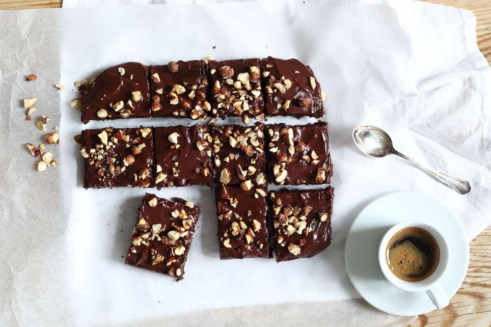 Browniebitar på bakplåtspapper och kopp med kaffe.