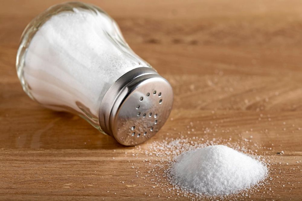 Saltströare vält omkull på träbord med saltspill.