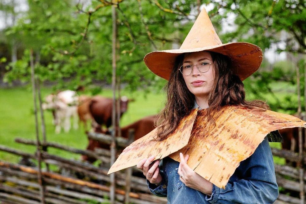 Naturligtvis går det lika bra med näver. Slöjdaren Kristin Sundberg provar forna tiders regnkläder nere vid kohagen på gården i Storvik.