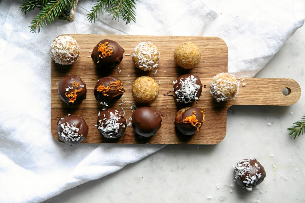 Chokladbollar med kokos och apelsinskal på en träbricka.