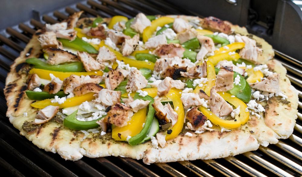 Pizzan toppas med pesto, kyckling och smulad fetaost - eller någonting annat du tycker om.