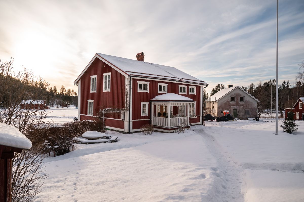 Röd trävilla i snötäckt landskap med veranda en vinterdag