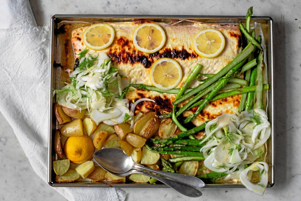 Ugnsbakad lax med citron, sparris och potatis på en plåt.