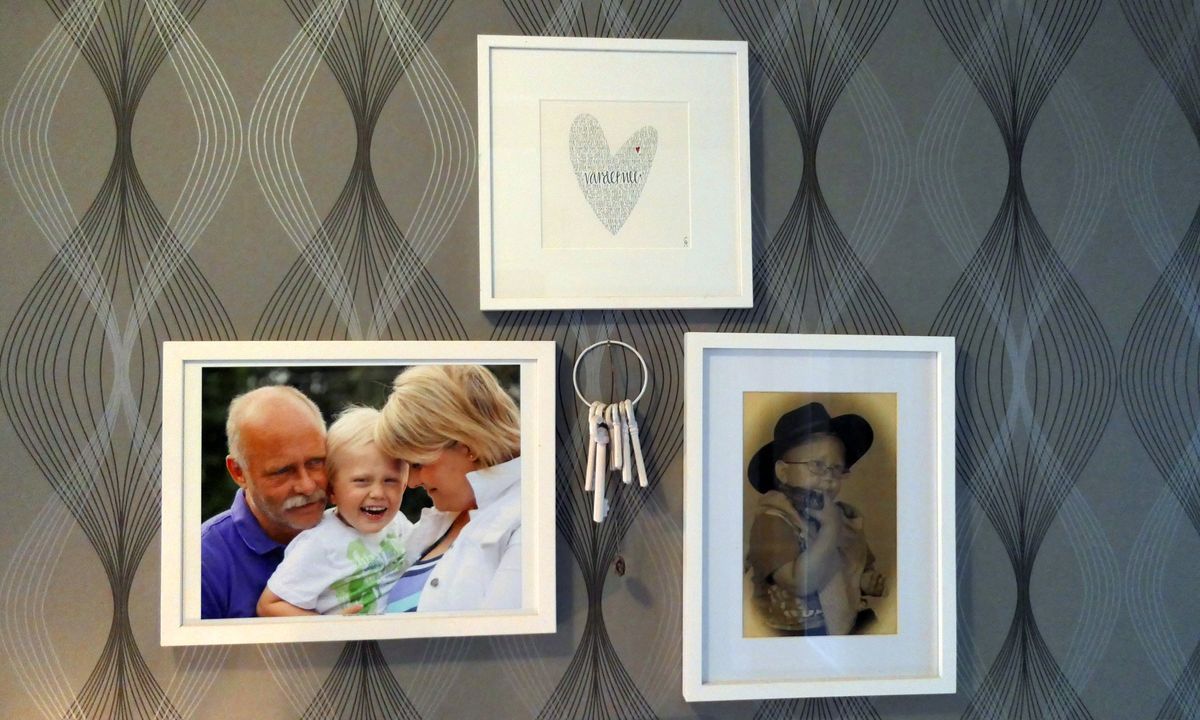 Tre inramade foton och en nyckelknippa hänger på en mönstrad vägg