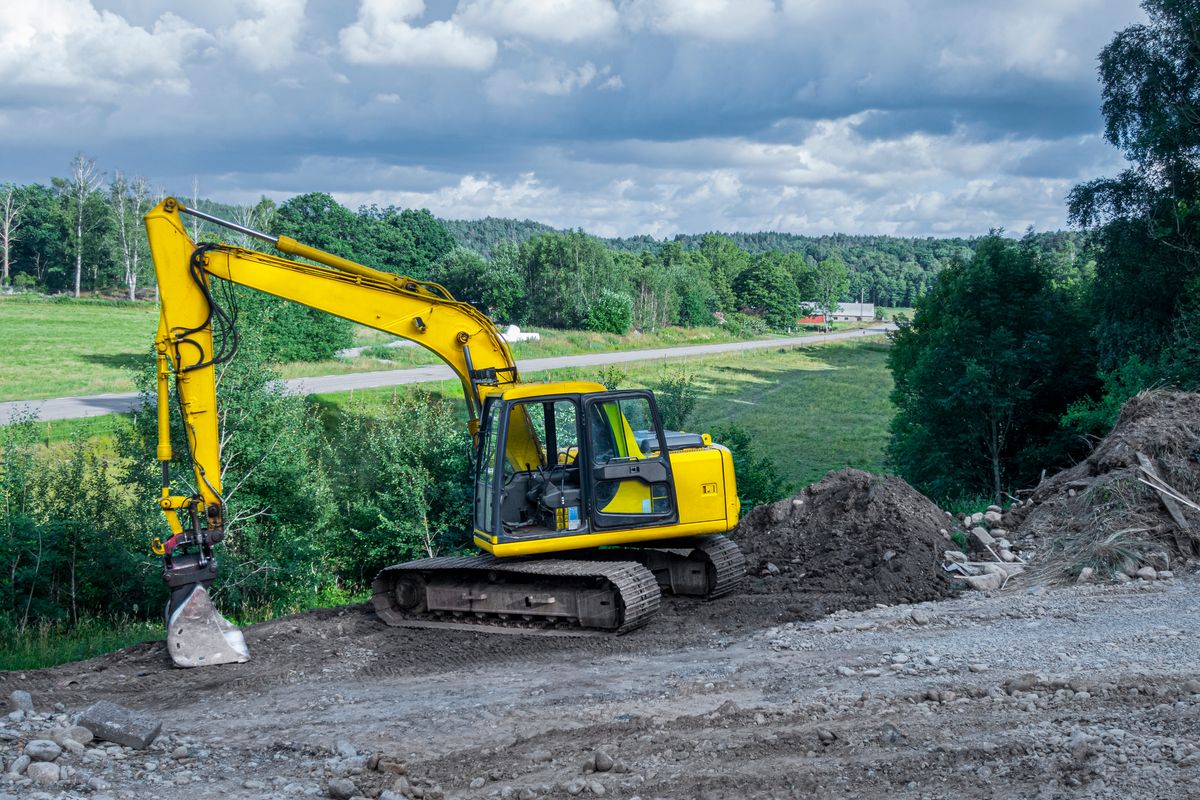 Yellow excavator in working site with a wonderful view over a rural landscape