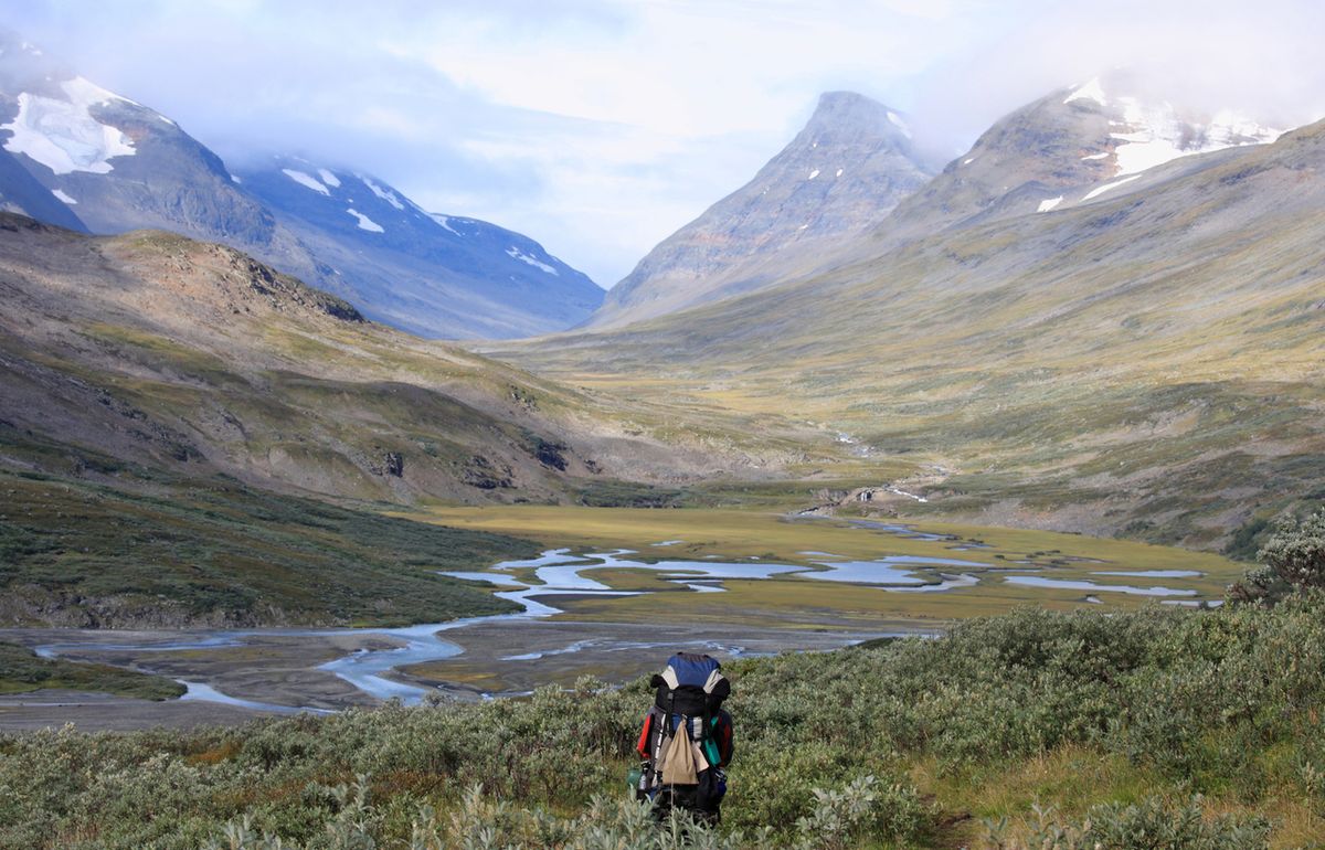 Fjällvandrare i videsnår med stor ryggsäck.