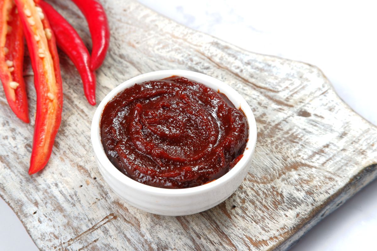 Skål med röd chilipasta Gochujang på ett rustikt träunderlag