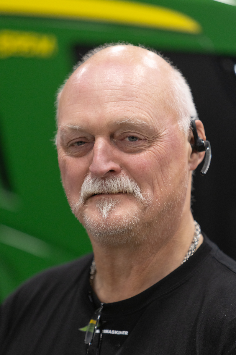 Man står framför grön traktor